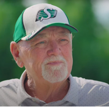 White, cis older man, in his 70s, white goatee and a green and white ballcap